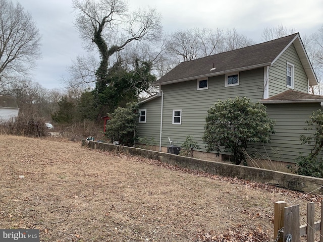 view of property exterior featuring a shingled roof and central AC unit