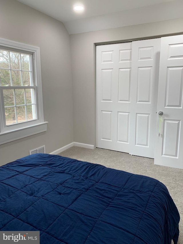 bedroom featuring a closet, visible vents, vaulted ceiling, and carpet flooring