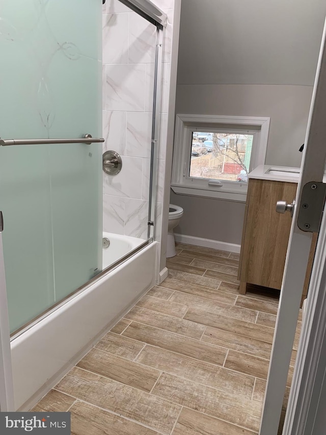 bathroom with toilet, baseboards, combined bath / shower with glass door, and wood finish floors