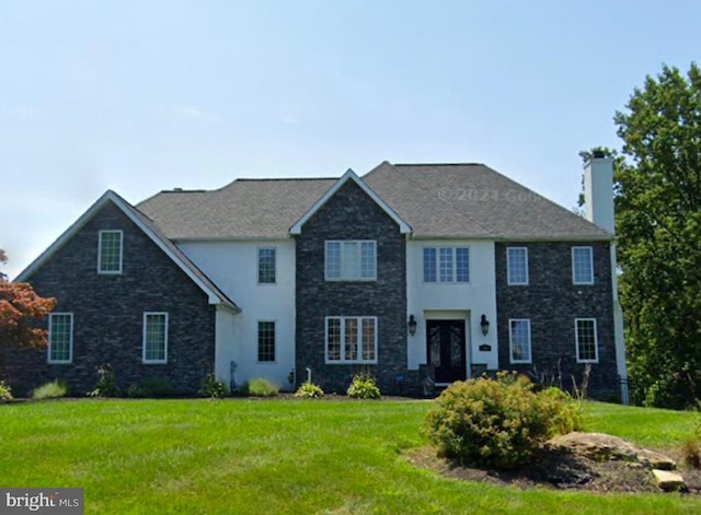 colonial home featuring a chimney and a front lawn