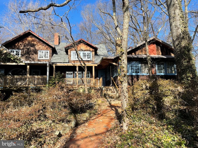 view of front facade featuring covered porch and a chimney