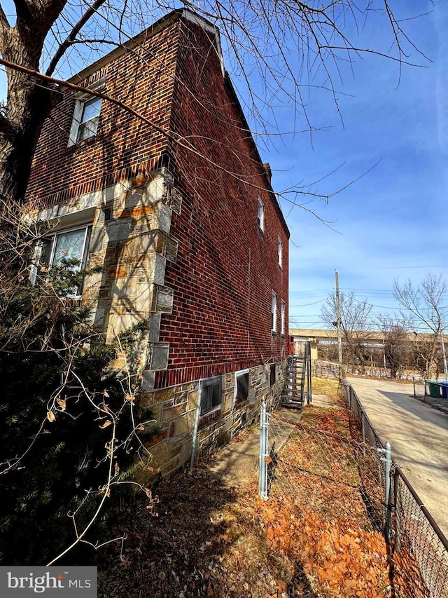 view of side of property featuring brick siding and fence