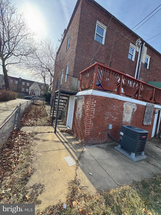 rear view of house with central air condition unit, brick siding, fence, stairway, and a patio area