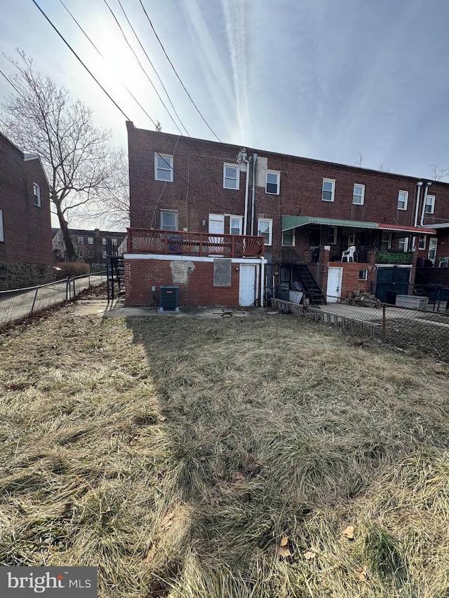 back of house with cooling unit, brick siding, and fence