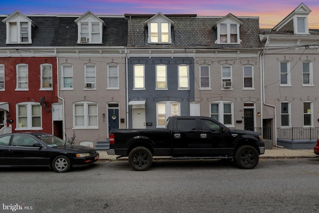 view of property with brick siding and mansard roof