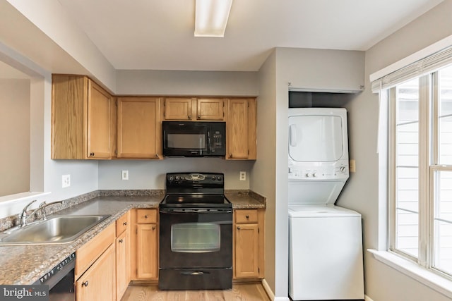 kitchen with sink, stacked washer / drying machine, black appliances, and light hardwood / wood-style floors