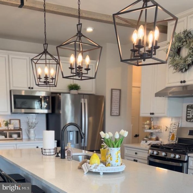 kitchen featuring white cabinetry, appliances with stainless steel finishes, tasteful backsplash, and decorative light fixtures