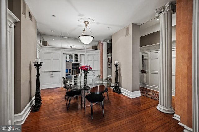 dining space featuring baseboards, dark wood finished floors, visible vents, and ornate columns