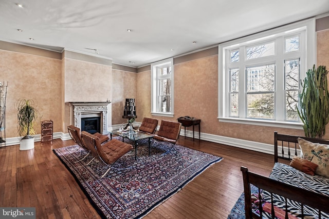 living room featuring dark wood-type flooring, a fireplace, baseboards, and ornamental molding