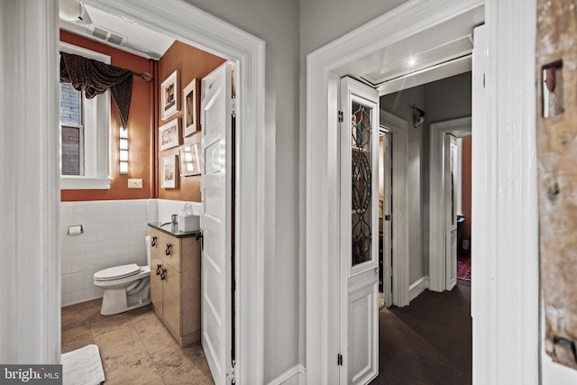 bathroom featuring toilet, tile walls, and wainscoting