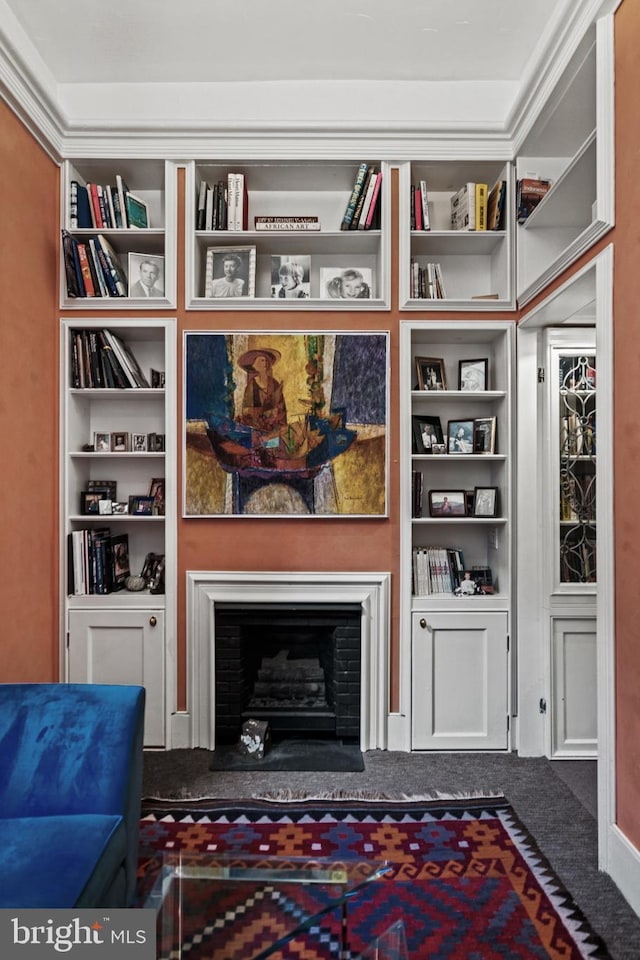 living area with a fireplace with raised hearth, dark colored carpet, and built in features