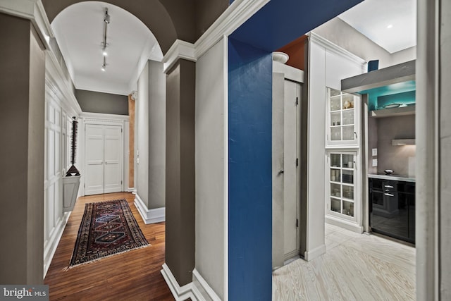 hall featuring light wood-style floors, arched walkways, and baseboards