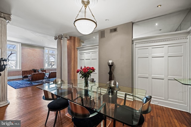 dining area featuring visible vents, dark wood finished floors, and ornate columns