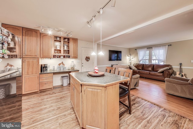 kitchen featuring open shelves, light countertops, a kitchen island, light wood-type flooring, and a kitchen breakfast bar