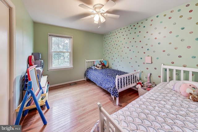 bedroom featuring baseboards, ceiling fan, light wood finished floors, and wallpapered walls