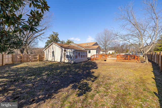 back of property featuring a deck, a yard, and a fenced backyard