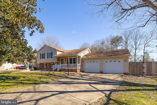 tri-level home featuring driveway, an attached garage, fence, a front lawn, and a porch