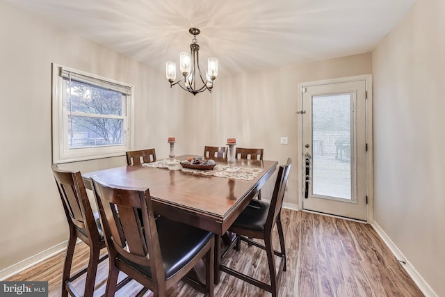 dining area featuring a notable chandelier, baseboards, and wood finished floors