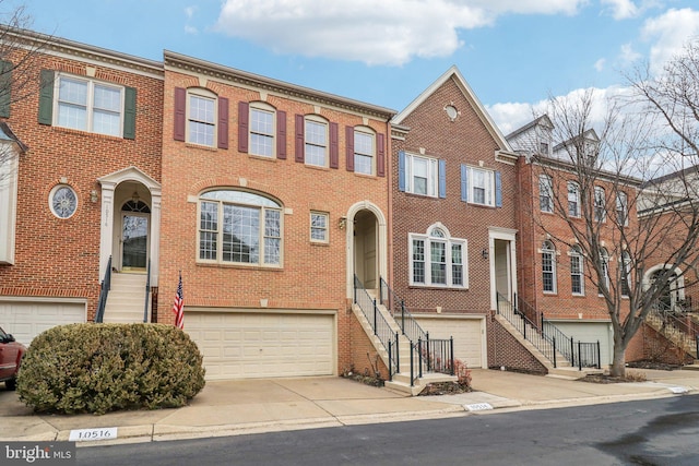 view of property with a garage, brick siding, driveway, and stairway