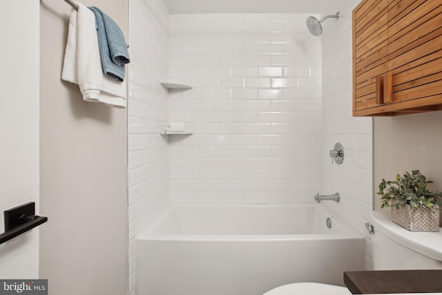 bathroom featuring toilet and tiled shower / bath