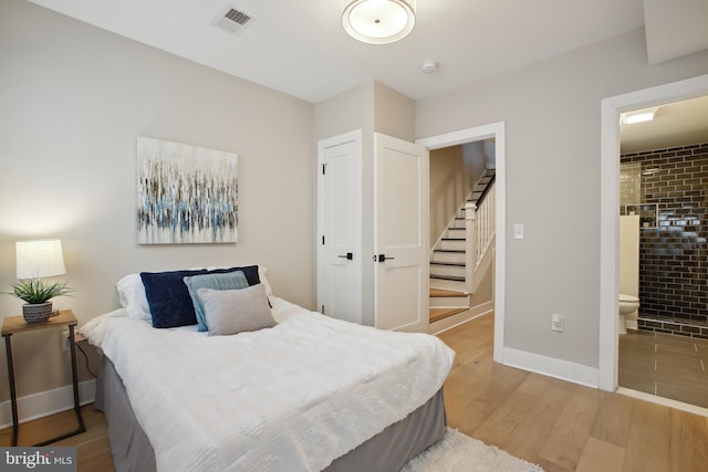 bedroom with light hardwood / wood-style floors and connected bathroom