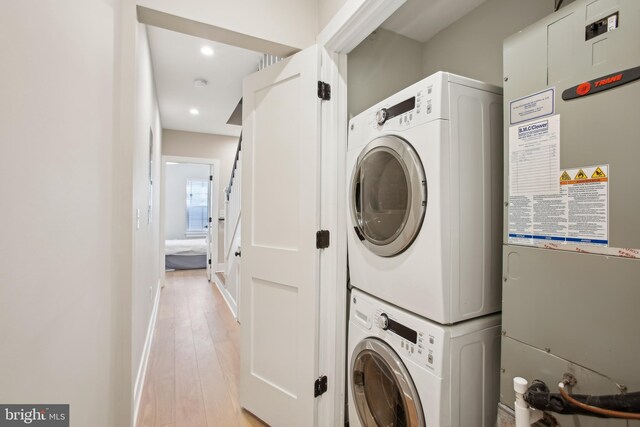 washroom with stacked washing maching and dryer and light wood-type flooring