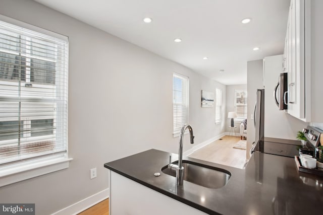 kitchen with white cabinetry, appliances with stainless steel finishes, sink, and light hardwood / wood-style floors