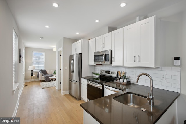 kitchen featuring light hardwood / wood-style floors, sink, appliances with stainless steel finishes, white cabinets, and decorative backsplash