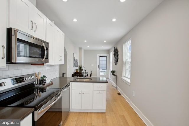 kitchen featuring sink, stainless steel appliances, kitchen peninsula, white cabinets, and decorative backsplash