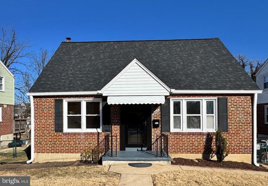 view of front of house with roof with shingles and brick siding