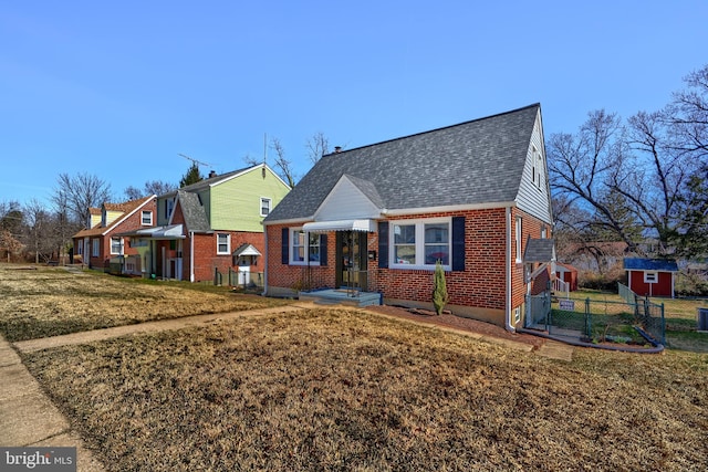 bungalow-style house with brick siding, roof with shingles, a front lawn, and fence