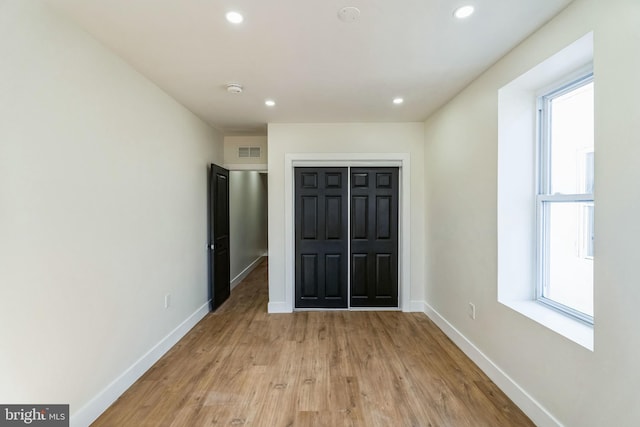 unfurnished bedroom featuring a closet, light hardwood / wood-style floors, and multiple windows