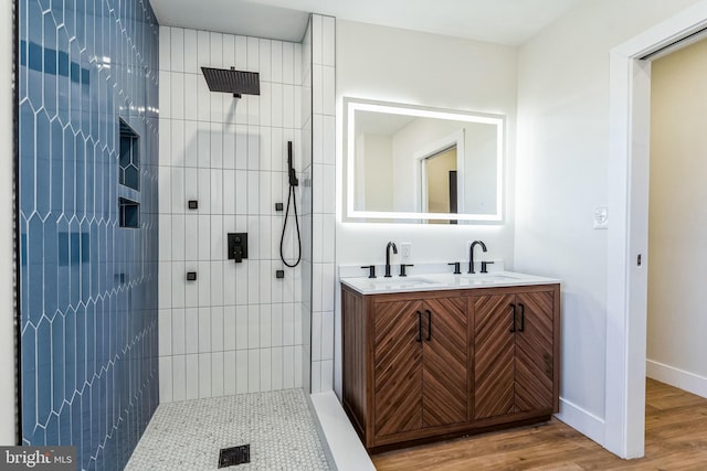 bathroom featuring hardwood / wood-style flooring, tiled shower, and vanity