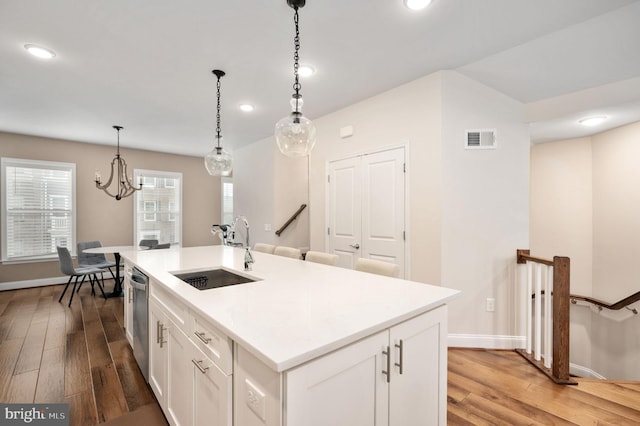 kitchen featuring pendant lighting, dishwasher, white cabinetry, sink, and a center island with sink