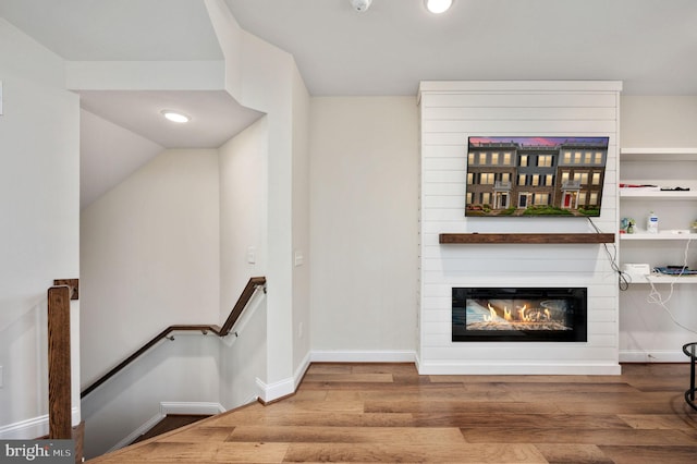 interior space with hardwood / wood-style floors, vaulted ceiling, and a large fireplace