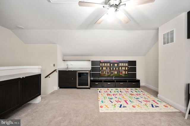 carpeted living room featuring vaulted ceiling, indoor bar, beverage cooler, and ceiling fan