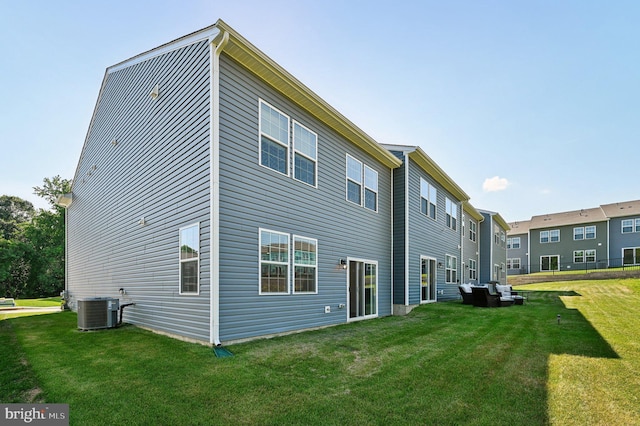 rear view of property featuring cooling unit and a lawn