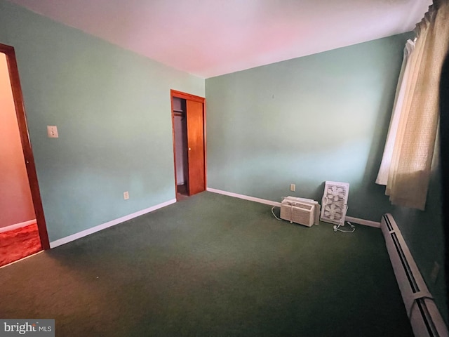 carpeted empty room featuring a baseboard radiator