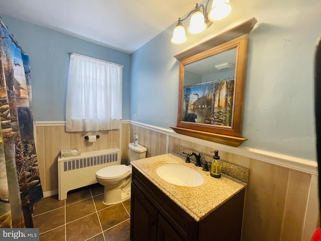 bathroom featuring vanity, radiator heating unit, tile patterned flooring, toilet, and wooden walls