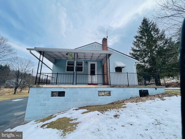 snow covered property with covered porch