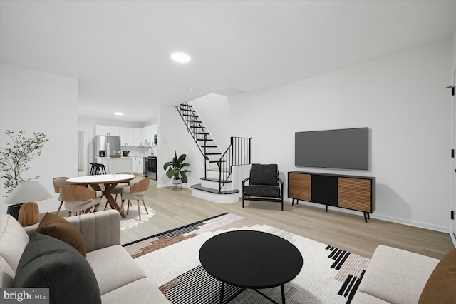 living area with light wood-style floors, recessed lighting, stairway, and baseboards