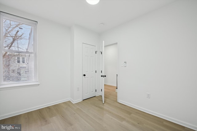 unfurnished bedroom featuring light wood-style flooring, baseboards, and a closet