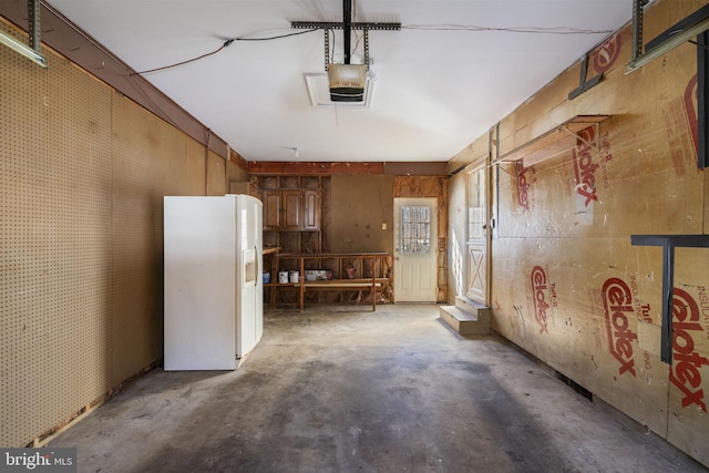 garage featuring a garage door opener and white refrigerator with ice dispenser