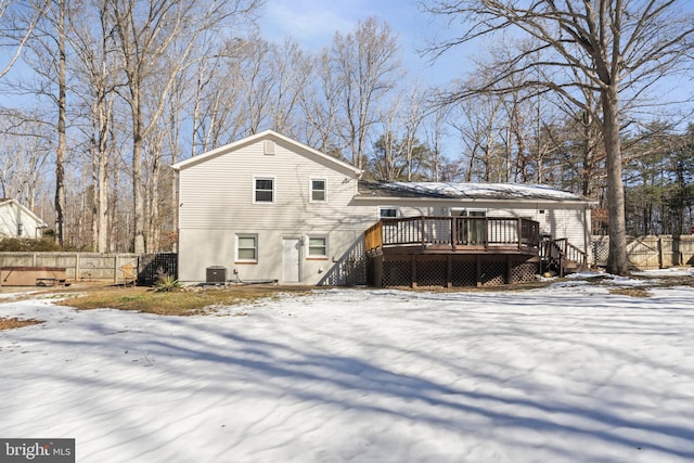 snow covered house with central AC unit and a deck