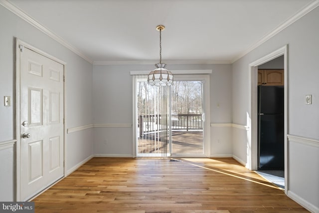 unfurnished dining area with ornamental molding and light wood-type flooring