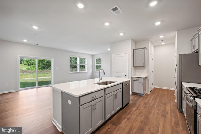 kitchen featuring stainless steel appliances, sink, a kitchen island with sink, and gray cabinetry