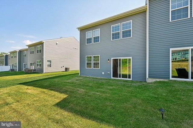 rear view of property with cooling unit and a lawn