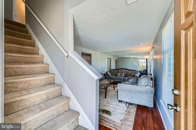 staircase with hardwood / wood-style floors and a textured ceiling