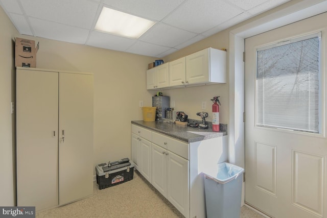 kitchen featuring a paneled ceiling and white cabinets