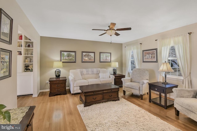 living room with built in features, ceiling fan, and light hardwood / wood-style floors